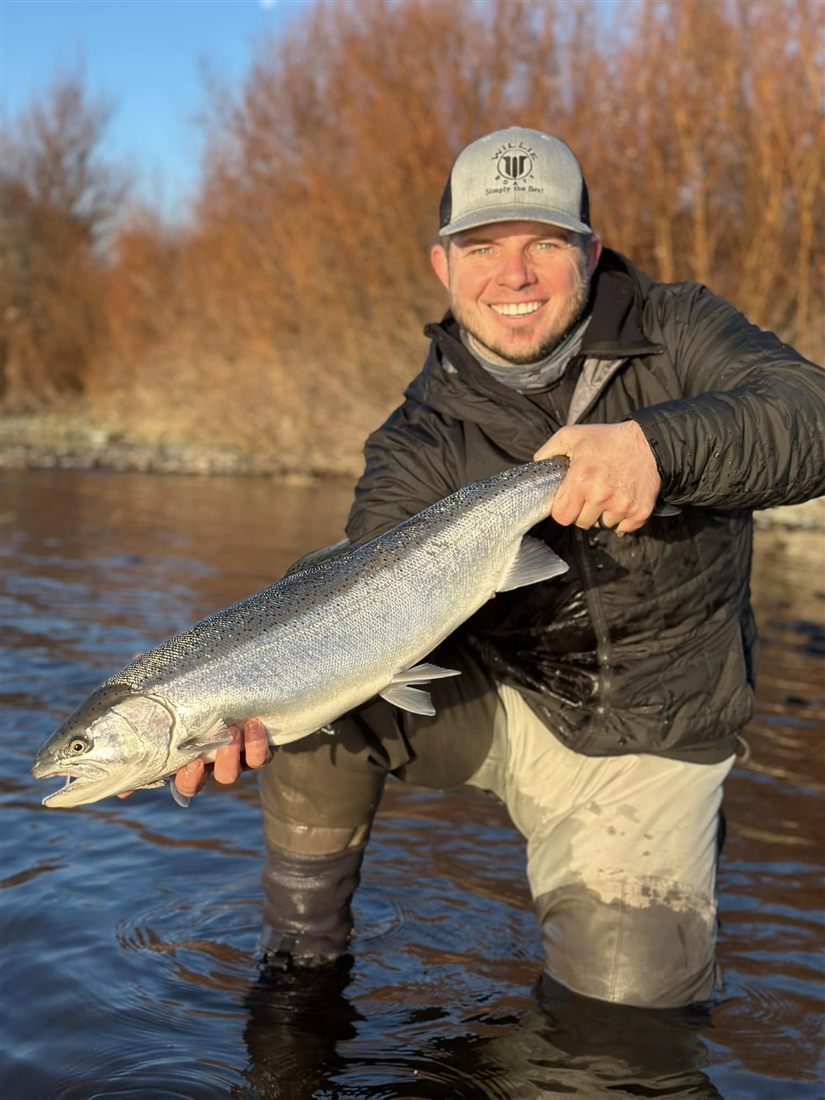 Captain Kyle Keith holding a chrome steelhead on the river